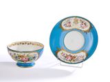 une tasse et une soucoupe posées sur un support à côté d'une assiette