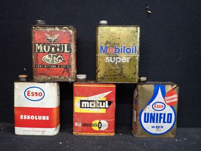 Plusieurs vieux bidons d'huile moteur sont alignés sur une surface noire