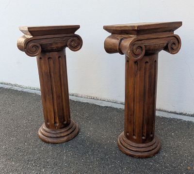 une paire de socles en bois sculpté posés sur le trottoir devant un mur blanc