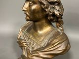 un gros plan sur un buste en bronze représentant une femme aux cheveux longs