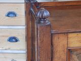 a bed with a wooden headboard and drawers in the background