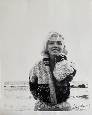 black and white photograph of a woman holding a teddy bear on the beach