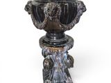 a black vase on a pedestal on a white background
