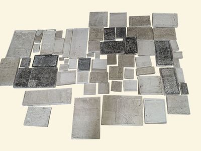 une photo montrant une pile de carreaux argentés posés sur une table