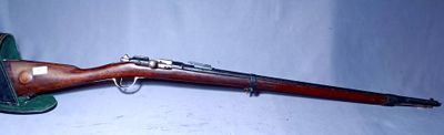 an old rifle is laying on a white surface with a blue background