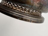 a large silver bowl on a stand on a white surface