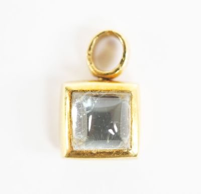 a close up of a gold plated pendant with a square stone