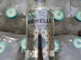 a bottle of gin sitting on a bed with a blue and white pattern on it