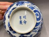 someone is holding a blue and white bowl with chinese writing on it