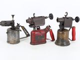 three antique cast iron tools are lined up on a white surface