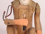 une sculpture en bois représentant un singe tenant un marteau à la main