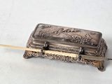 une vieille boîte en argent munie d'une poignée en bois, posée sur une surface blanche