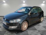 La Volkswagen Polo noire est garée dans une pièce au sol carrelé.