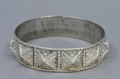 a close up of a silver bracelet on a gray surface