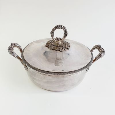 a silver pot with a handle on a white surface