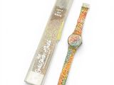 une image représentant une montre et une boîte de paillettes posées sur une surface blanche