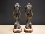 pair of bronze figurines of a woman holding a basket of flowers