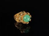 a gold ring with a green stone surrounded by diamonds on a black surface