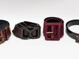 three belts with buckles are lined up on a white surface
