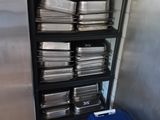 many trays of food sitting on a shelf in a kitchen