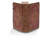 un vieux livre à la couverture rouge posé sur une surface blanche