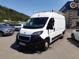 La camionnette blanche est garée devant un immeuble sur lequel est accrochée une pancarte.