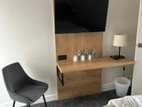 a bed and a chair in a room with a flat screen tv on the wall