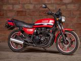a red and black motorcycle parked in front of a brick wall