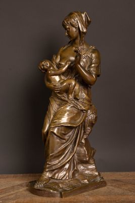 a bronze statue of a woman holding a child on a wooden table