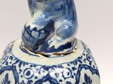 a blue and white vase with a bear on top of it