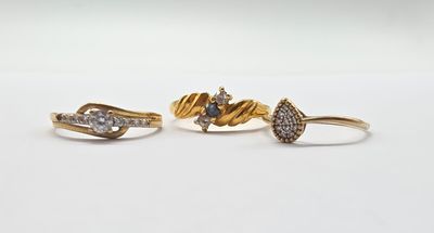 trois bagues en or serties de diamants, posées sur un fond blanc