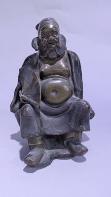 une petite statue représentant un homme assis sur une chaise