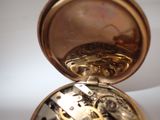 a close up of a pocket watch on a white surface