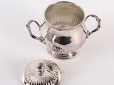 a silver cup with a lid sitting on a table
