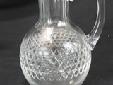 a clear glass pitcher with a handle on a black table
