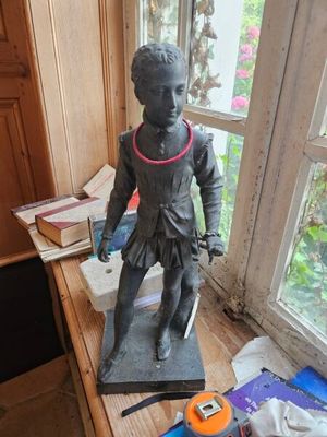 une statue représentant un garçon debout sur un bureau près d'une fenêtre