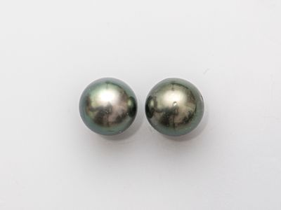 a pair of black pearls on a white surface