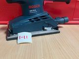un gros plan d'une ponceuse filaire posée sur une table en bois