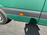 a shadow of a person standing in front of a green bus
