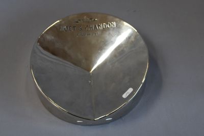un objet argenté posé sur une table, sur fond blanc