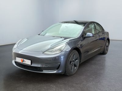 La Tesla Model 3 est garée dans une pièce au sol noir.