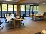 Il y a de nombreux bureaux et chaises dans ce bureau qui donne sur l'extérieur.