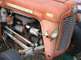 an old rusted orange tractor sitting in the grass