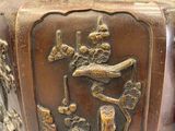 a bronze vase with a bird and flowers on it