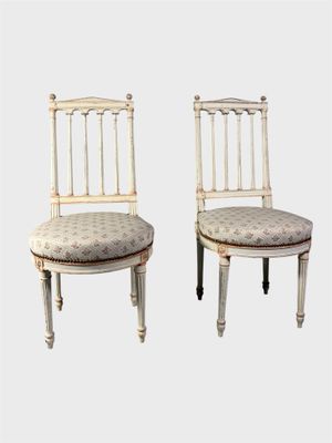 une paire de chaises peintes en blanc, avec des coussins d'assise rembourrés à motifs floraux