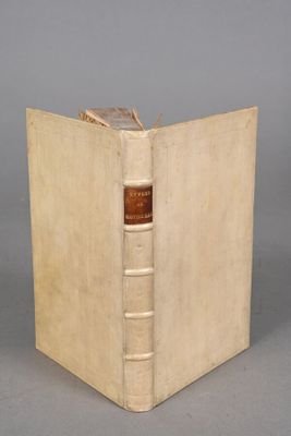 un vieux livre posé sur une table à côté d'un mur gris