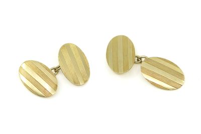 une paire de boutons de manchette plaqués or sur fond blanc