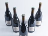 six bottles of wine are lined up in a row on a white surface