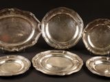 six silver plated dishes on a black background