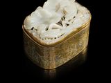 une boîte dorée contenant des fleurs blanches, posée sur un fond noir